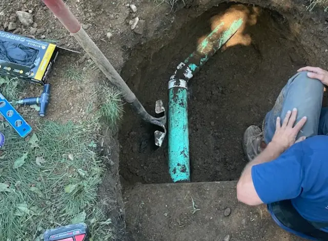 New green PVC sewer connection in an excavated hole