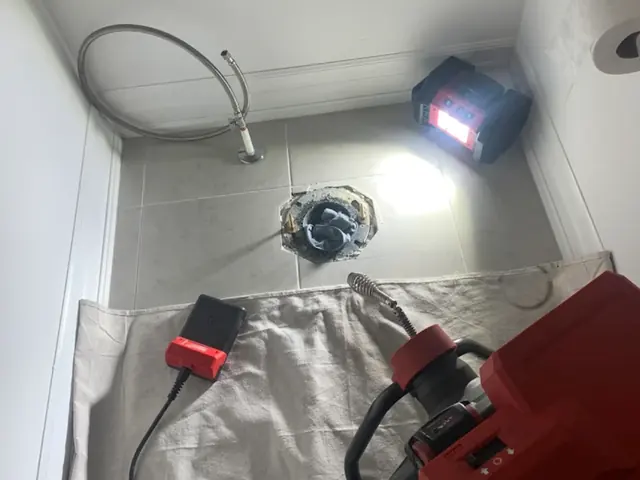 Toilet drain opened up with a drain machine on a drop cloth
